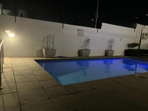 a swimming pool with potted plants and an umbrella at Cozy retreat in Carlswald 264 in Midrand