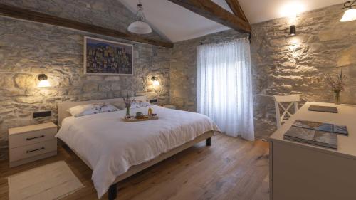 a bedroom with a bed and a stone wall at Villa Casa Pintori in Buzet
