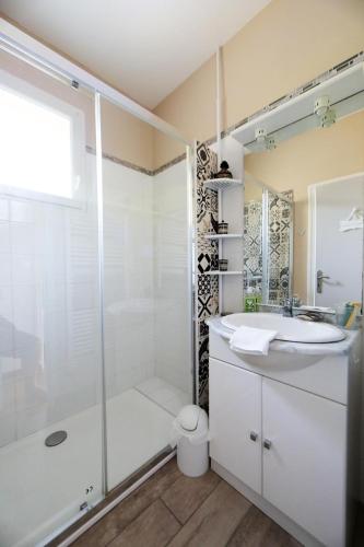 une salle de bain blanche avec une douche et un lavabo dans l'établissement Appartement les hirondelles, à Saint-Pair-sur-Mer