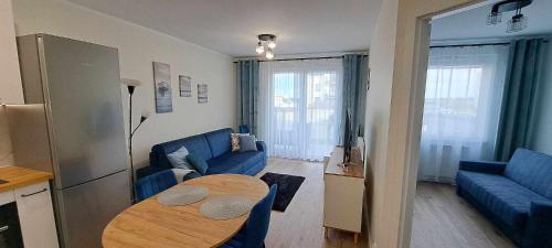 ein Wohnzimmer mit einem Tisch und einem blauen Sofa in der Unterkunft Apartament Morelowa in Władysławowo