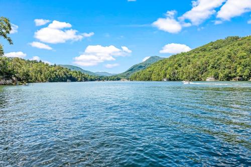 a boat on a lake with mountains in the background at Water's Edge Holmstead in Lake Lure