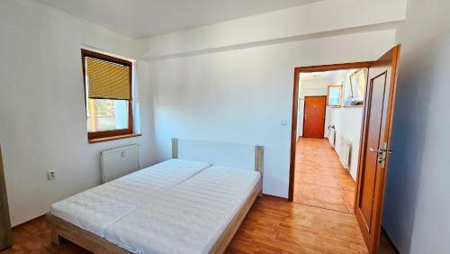 a white bedroom with a bed and a hallway at Apartmán Bulvár in Žilina