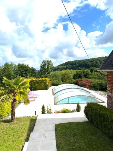 un jardin avec un palmier et une piscine dans l'établissement La Villa Bucaille à Camembert avec sa Vue panoramique-10p, à Camembert