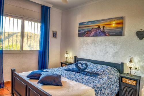a bedroom with a bed with blue pillows on it at Casa Hollandia in Viñuela