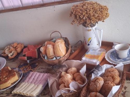 a table with baskets of bread and a vase of flowers at Pouso de Teria in Tiradentes