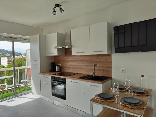 - une cuisine avec des placards blancs et une table avec des verres dans l'établissement Splendide T2, 200m de la mer, climatisé, parking, à Cagnes-sur-Mer