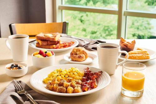 a table topped with plates of breakfast foods and orange juice at Holiday Inn Baton Rouge College Drive I-10 by IHG in Baton Rouge