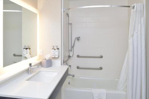 a white bathroom with a sink and a shower at Holiday Inn Express Hotel & Suites Carthage by IHG in Carthage