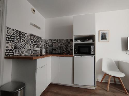 une cuisine avec des armoires blanches et un micro-ondes dans l'établissement Studio sur cour, Centre-ville, à Morlaix