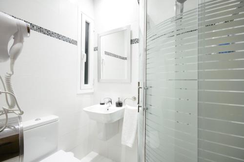 y baño blanco con lavabo y ducha. en Pensión San Jerónimo, en San Sebastián