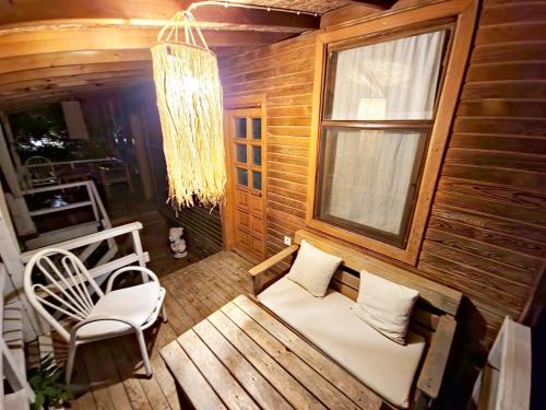 a porch with a bench and a window and a chandelier at Simurg Evleri Olympos in Olympos