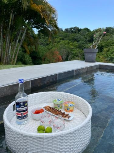 een witte tafel met eten en een fles water bij VILLA ZEN in Petit-Bourg