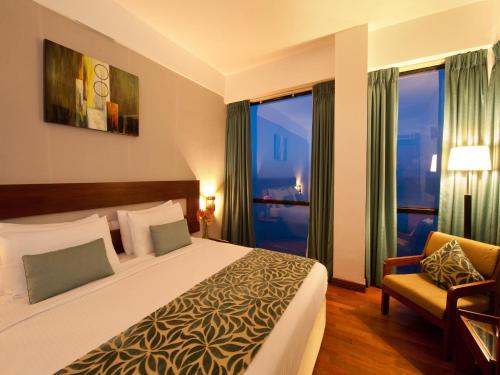 a hotel room with a bed and a chair and windows at The Ocean Colombo in Colombo