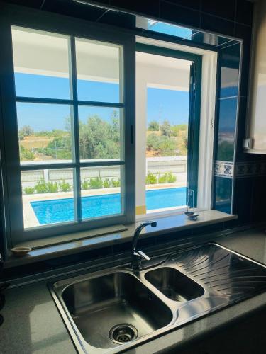 a kitchen with a sink and a window above a kitchen counter at Vivenda Soares in Estômbar