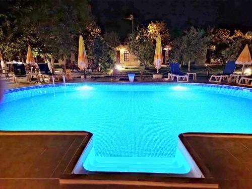 a swimming pool at night with chairs and umbrellas at Simurg Evleri Olympos in Olympos