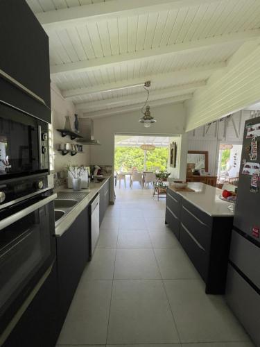 Una cocina con gabinetes negros y piso de baldosas blancas. en VILLA ZEN, en Petit-Bourg