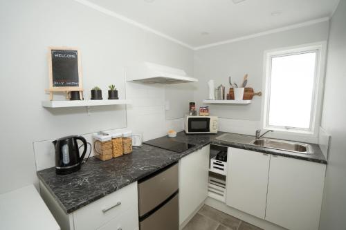 a kitchen with white cabinets and a black counter top at The Billy Hilton in Tauranga