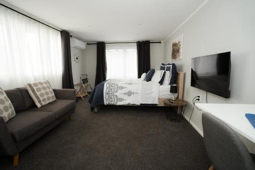a bedroom with a bed and a couch and a tv at The Billy Hilton in Tauranga
