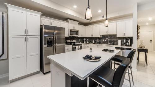 a kitchen with white cabinets and a large island with chairs at The Monochrome in Orlando