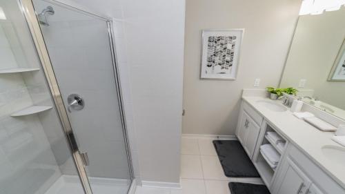 a white bathroom with a shower and a sink at The Monochrome in Orlando
