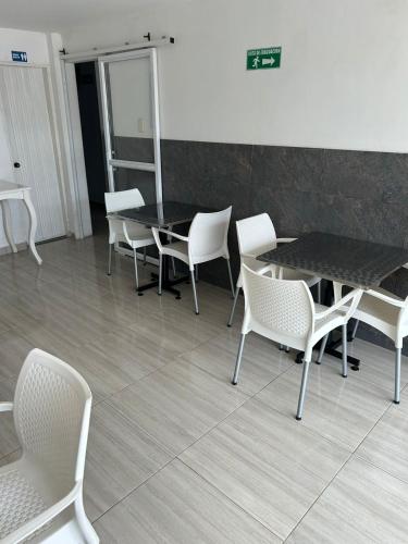 a dining room with white chairs and a table at Hotel Encanto Vallenato in Valledupar