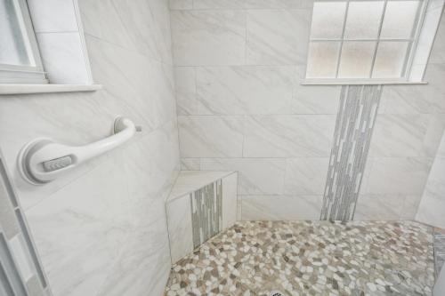 a bathroom with a shower with a glass shelf at Cape Paradise B & B - Your Luxury Tropical Retreat in Cape Coral