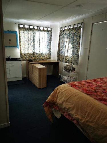 a bedroom with a bed and a desk and windows at Affordable and convenient accommodation in Toowoomba