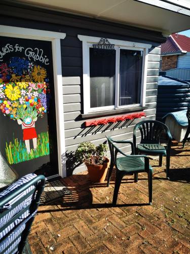 a house with two chairs and a window and a sign at Affordable and convenient accommodation in Toowoomba