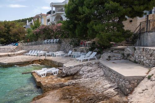a group of white chairs sitting on the side of the water at Apartments Ivica in Primošten