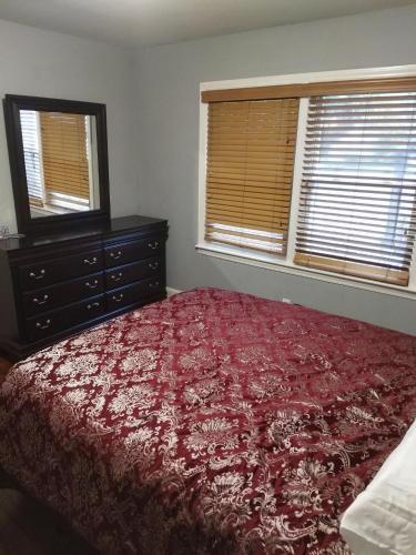 a bedroom with a bed and a dresser and two windows at Queen city lifestyle in Charlotte