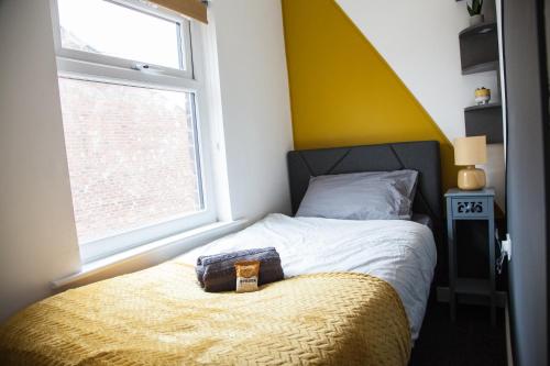 a bedroom with a bed with a yellow headboard and a window at Entire Modern Home in Manchester and Near Peak District in Manchester