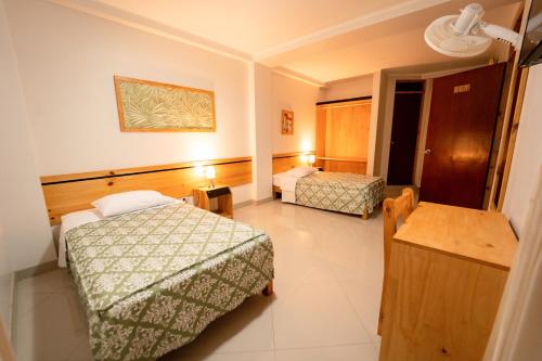 a hotel room with two beds and a table at Hostal Los Balcones in Nazca
