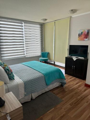 a bedroom with a bed and a flat screen tv at Condominio Mar Egeo Iquique in Iquique