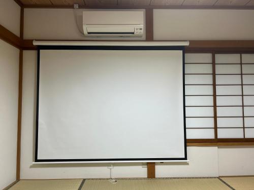 a large white screen in a room with a microwave at 南箱根 熱海 貸切別荘 リゾートハウス バンボー in Kannami