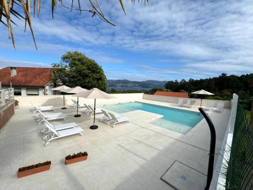a swimming pool with chairs and umbrellas next to a house at Naturmar in Raxó