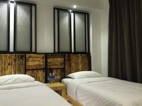 twee bedden naast elkaar in een kamer bij The Oikos Hotel in Pontian Kecil