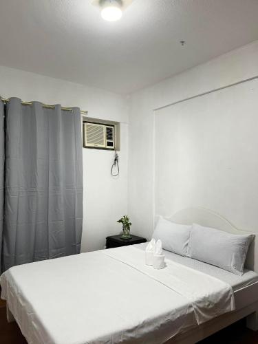 a bedroom with a white bed and a window at 2BR Kelsey Haven With Balcony in Davao City