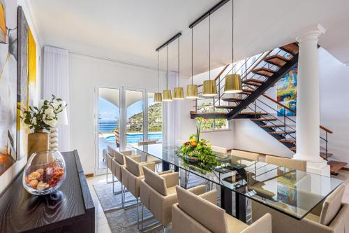 a dining room with a glass table and chairs at Luxury villa with private heated pool, garden and views of the sea and mountains. in Arco da Calheta