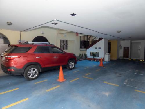 a red suv parked in a garage with orange cones at Hotel El Ejido in Quito