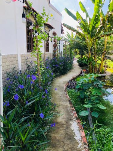 a garden in front of a house with purple flowers at Cóc Retreat Mỹ Tho City in My Tho