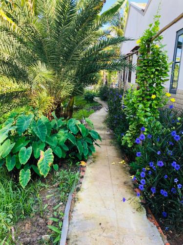 a sidewalk in a garden with plants and flowers at Cóc Retreat Mỹ Tho City in My Tho