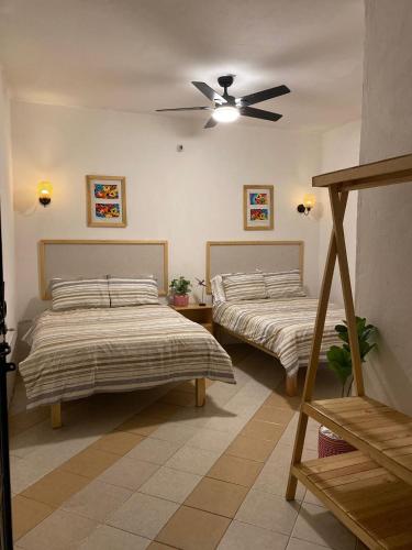 a bedroom with two beds and a ceiling fan at Casa Cataleya Refugio Bohemio y Romántico en Oaxaca in Oaxaca City