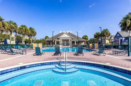 a swimming pool with chairs and a house in the background at Vilas em Seven Dwarfs - 3 Quartos - 20 min disney in Kissimmee