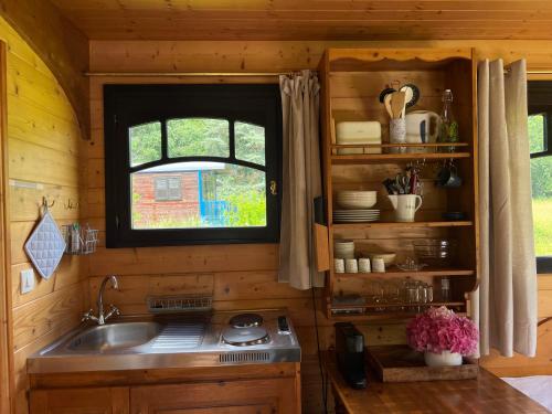 une cuisine avec un évier et une fenêtre dans l'établissement Les roulottes de Fonroques - logement insolite dans la nature, à Montcaret