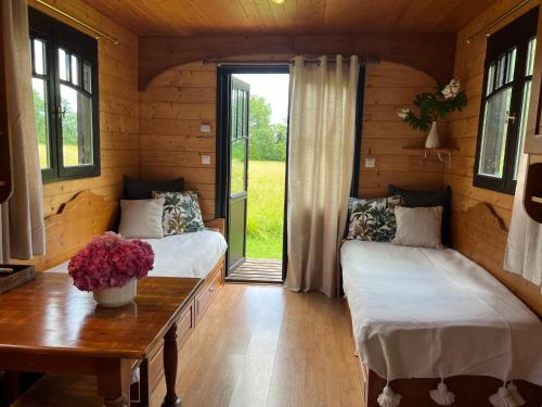 - 2 lits dans une chambre avec une table et une fenêtre dans l'établissement Les roulottes de Fonroques - logement insolite dans la nature, à Montcaret
