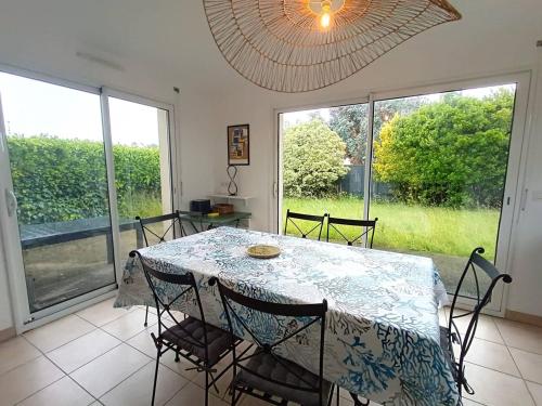 une salle à manger avec une table, des chaises et des fenêtres dans l'établissement Maison 3 ch. avec jardin, terrasse et WIFI à 480m de la plage et 200m du port à Ploumanac’h - FR-1-368-429, à Perros-Guirec