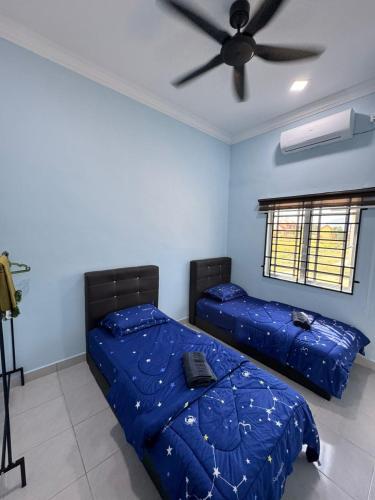 a bedroom with two beds and a ceiling fan at Afdal homestay in Pantai Cenang
