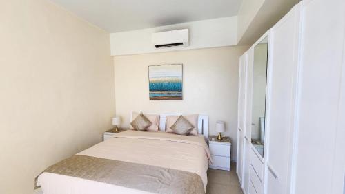 a white bedroom with a bed and a mirror at La Mirada Residences in Mactan