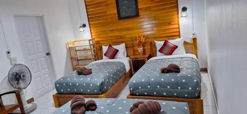 a room with two beds and a table with a fan at Khao Sok Holiday Resort in Khao Sok National Park