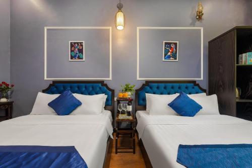 2 camas con almohadas azules y blancas en una habitación en Amanda Boutique Hotel & Travel, en Hanói
